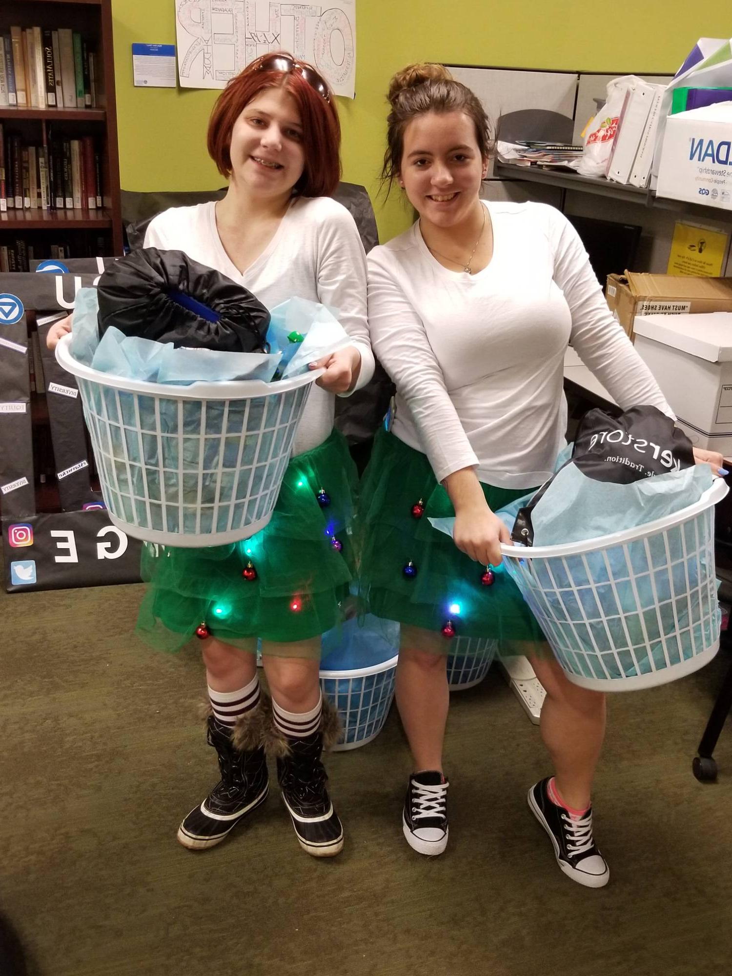 Two students smiling while holding laundry baskets